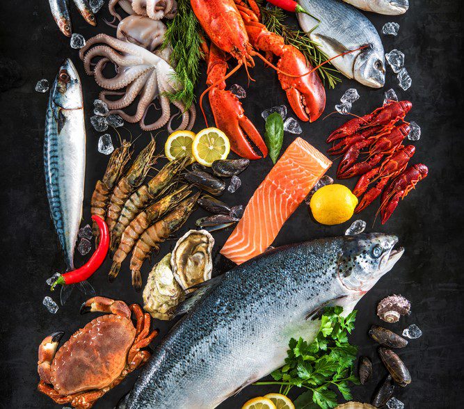 Fresh fish and seafood arrangement on black stone background
